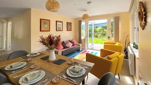 A dining area with a wooden table set for four, a sofa, and a yellow armchair. - 2 bedroom accommodation in Presteigne (Presteigne)