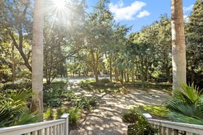 A pathway leading through a garden with trees and plants, surrounded by a white fence.