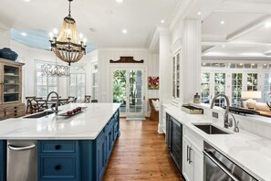 A spacious kitchen with a large island, white cabinetry, and a chandelier.
