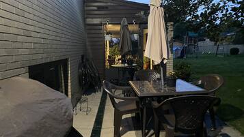An outdoor patio with a table and chairs, a covered umbrella, and potted plants.