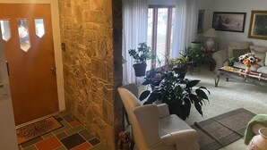 A living room with a stone wall, a sofa, a coffee table, and various potted plants.