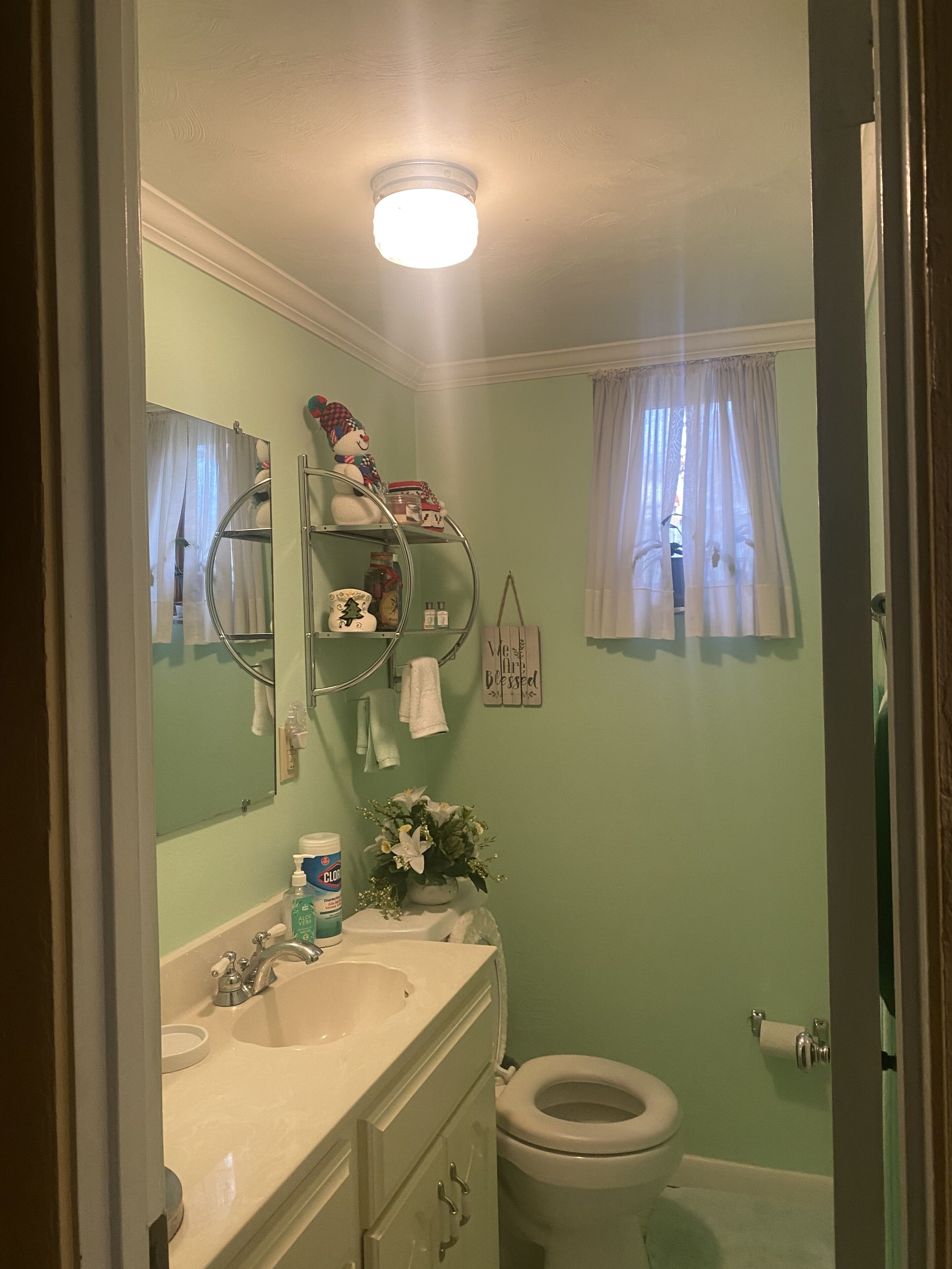 Casa de banho com uma sanita, lavatório branco e uma prateleira com produtos de higiene pessoal.