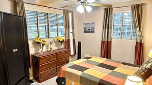 Ein Schlafzimmer mit Bett, Kommode und Deckenventilator.
