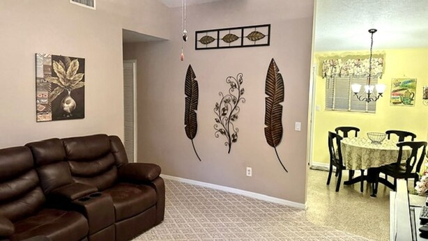 Ein Wohnzimmer mit braunem Ledersofa, Deckenventilator, Wanddekoration und einem Essbereich mit Tisch und Stühlen.