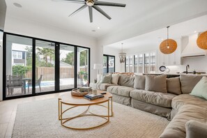 Relax in this spacious living room with a curved sofa, sliding glass door, and a pool view.