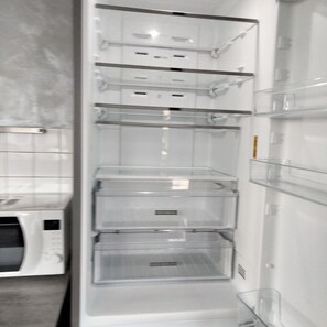 Een lege, witte koelkast met meerdere planken en een vriesvak.