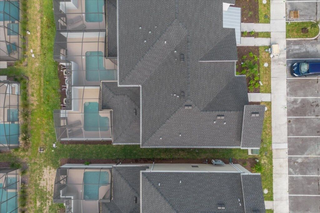 Luchtbeeld van een woonwijk met meerdere huizen, een parkeerplaats en een zwembad.