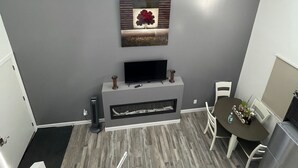A modern living room with a fireplace, a flat-screen TV, and a dining area with a table and chairs. - The Cottages@Gull&Castle#4 (Wasagaming)
