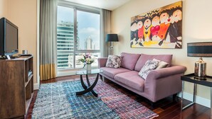 Una sala de estar moderna con un ventanal grande, un sofá rosa, una mesa de centro de vidrio y un cuadro en la pared.