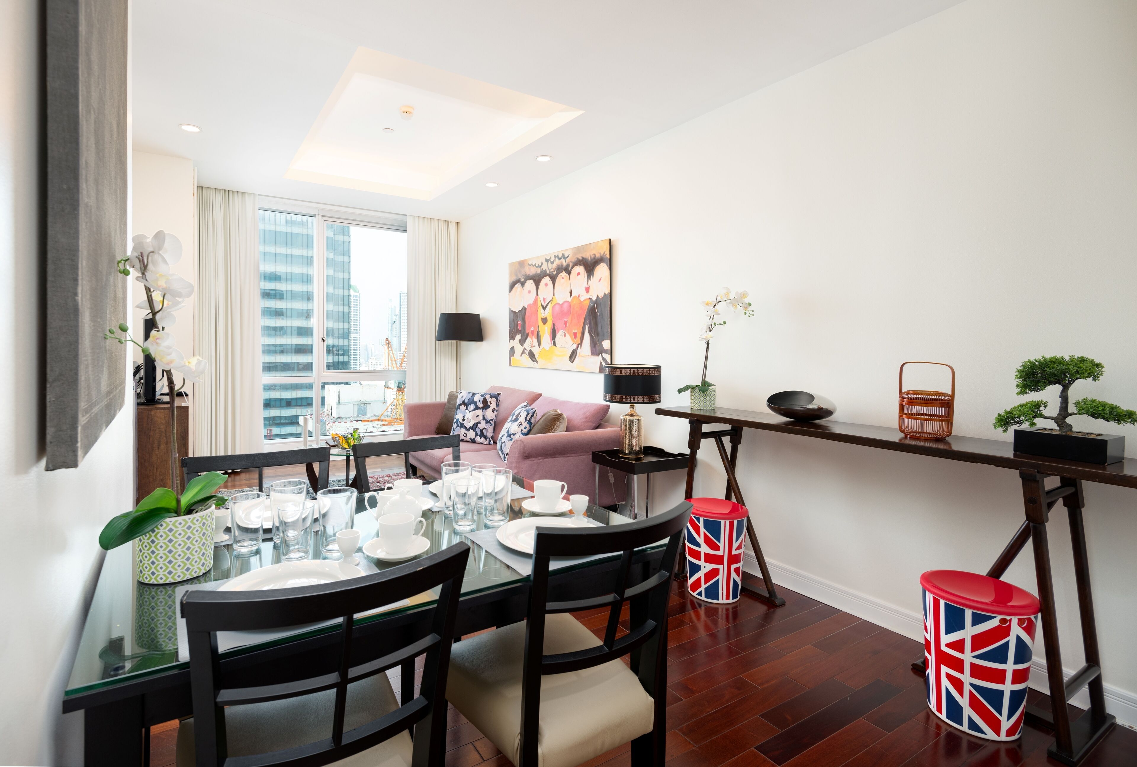 Un salon moderne avec un canapé, une table à manger pour quatre personnes et une grande fenêtre donnant sur la ville.