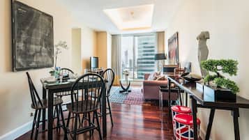 A modern living room with a dining area, a large window with a city view, and a ceiling light.