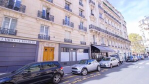A multi-story building with a row of parked cars on the street. - The Workshop Near Eiffel Tower by Mon Petit Faré (Paris)