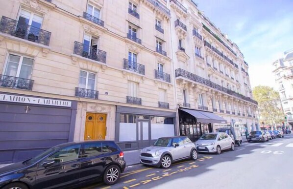 A multi-story building with a row of parked cars on the street. - The Workshop Near Eiffel Tower by Mon Petit Faré (Paris)