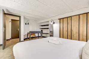Een slaapkamer met een groot bed, een bureau met stoel, een kledingkast en een spiegel.