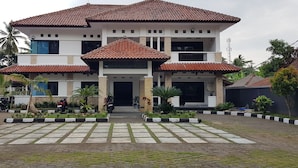 A two-story building with a tiled roof, a front entrance, and a paved driveway. - Hotel pondok putri (Cijulang)