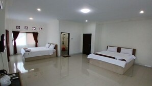 A hotel room with two beds, a television, and a small table with a basket. - Hotel pondok putri (Cijulang)
