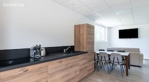 Cozy living space with a central kitchen, dining area, and flat-screen TV.