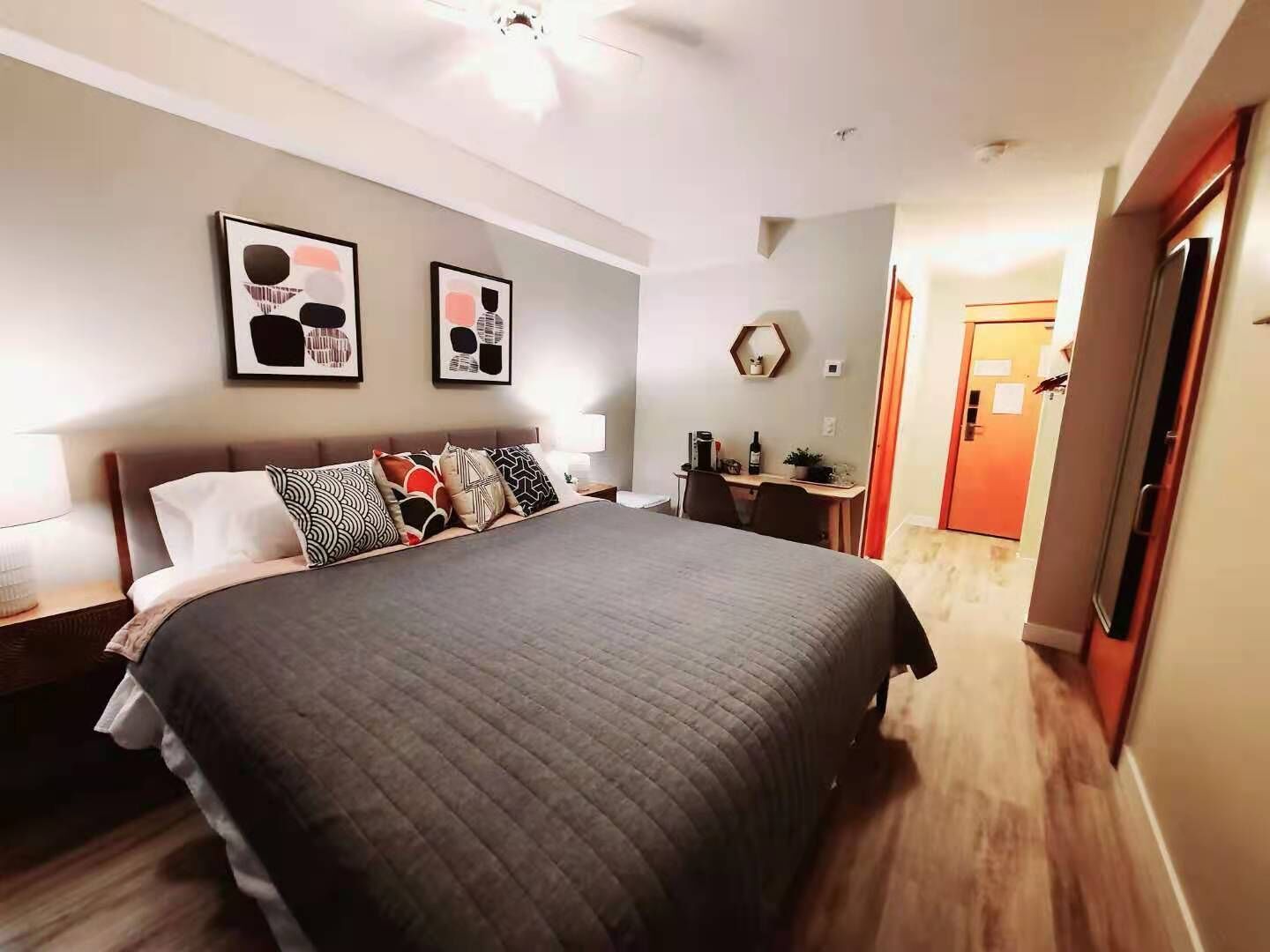 Une chambre moderne avec un grand lit, un bureau et une chaise. Deux tableaux encadrés ornent le mur.