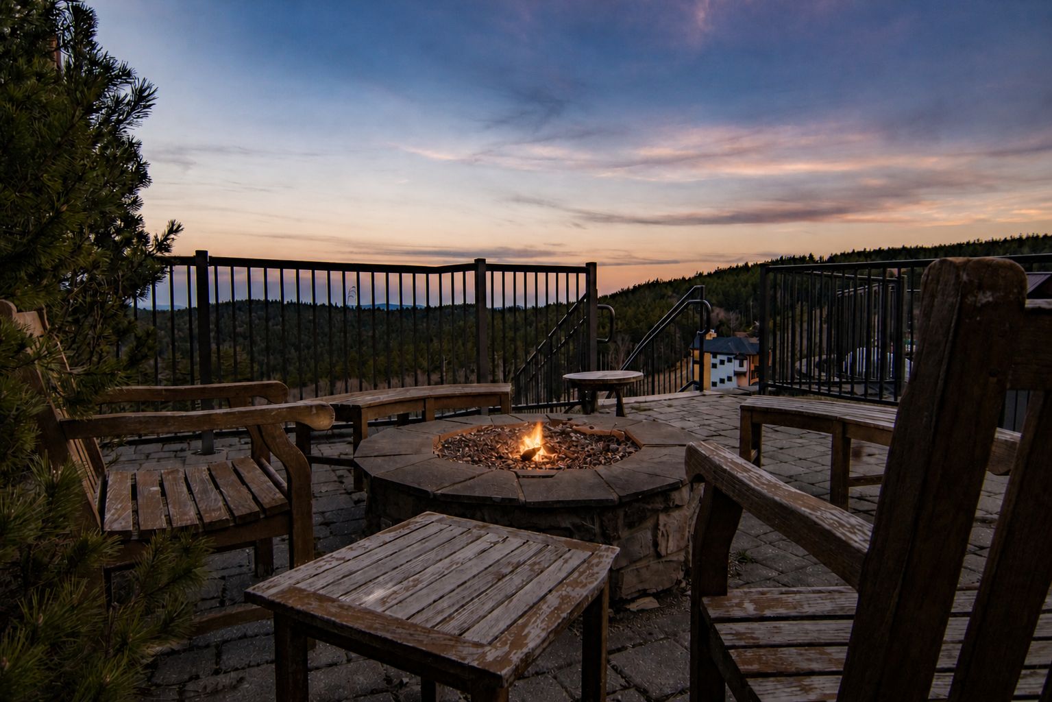 Eine Außenpatio mit einem Feuerkorb, Holzmöbeln und Blick auf die Berge.