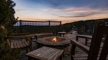 Eine Außenpatio mit einem Feuerkorb, Holzmöbeln und Blick auf die Berge.