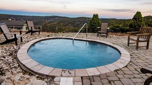 A circular pool with a metal ladder, surrounded by stone tiles and wooden chairs. - Ski-In Ski-Out•Hot Tub•King Bed•Sauna•Deck (Snowshoe)