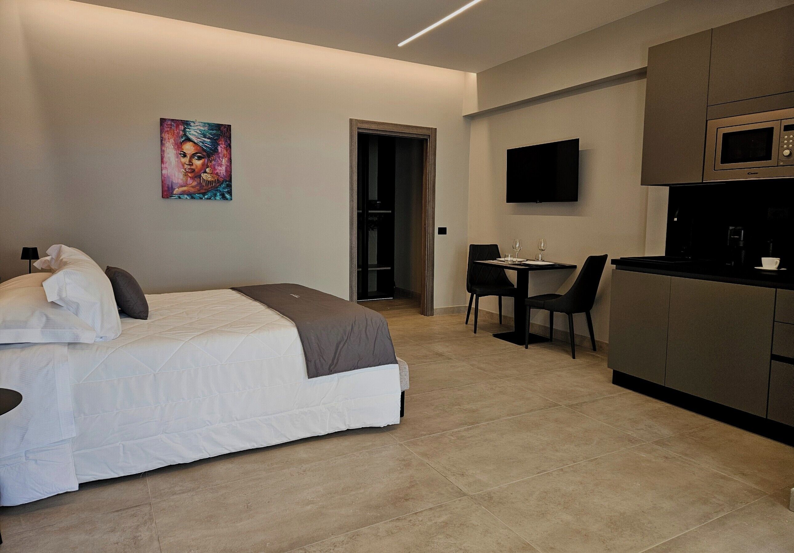 Una habitación de hotel moderna con cama, escritorio, silla, televisión de pantalla plana y microondas.