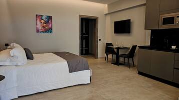 Una habitación de hotel moderna con cama, escritorio, silla, televisión de pantalla plana y microondas.