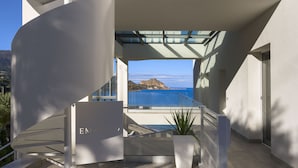 A modern building with a staircase leading to a balcony overlooking the sea. - Emerald Boutique Hotel (Cefalù)