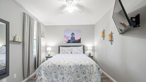 A bedroom with a large bed, a ceiling fan, a painting of a building, and wall-mounted sconces. - Brothers bond 3bed 2bath, short walk to the square (Covington)