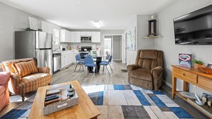 A modern kitchen with a dining area, a living room with a sofa and a coffee table, and a TV mounted on the wall. - Brothers bond 3bed 2bath, short walk to the square (Covington)