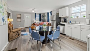 A modern kitchen with white cabinets, a round glass table, and blue chairs. - Brothers bond 3bed 2bath, short walk to the square (Covington)