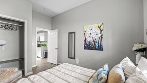 A bedroom with a bed, pillows, a painting, and a door leading to a bathroom. - Hollywood of the south 3bed 2bath, Short walk to the square (Covington)