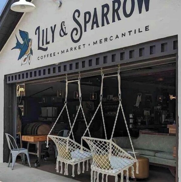 L’extérieur d’un café-épicerie appelé « Lily & Sparrow », avec des places assises en plein air.