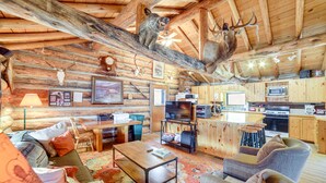 A rustic cabin interior with a wooden ceiling, a dining area, a kitchen with modern appliances, and a living room with a fireplace. - Yellowstone Cabin Getaway Near National Park (Cameron)