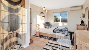 Un dormitorio con cama, mesita de noche y ventana.