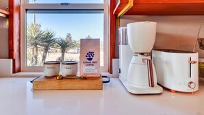 Una encimera de cocina con una cafetera, un tostador y frascos etiquetados como 'honey' y 'sugar'. También se ve un saco de granos de café.