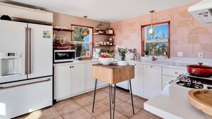 Una cocina moderna con armarios blancos, una isla de madera y una estufa roja.
