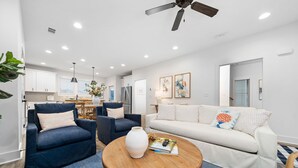 A modern living room with a blue armchair, a white sofa, and a wooden coffee table.