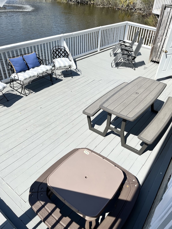A deck with a table and chairs, a bench, and a view of a body of water.