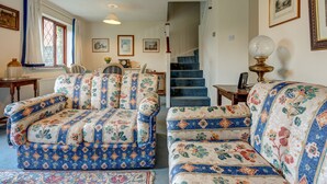 Uma sala de estar com sofás estampados, uma mesa de jantar e uma escada.