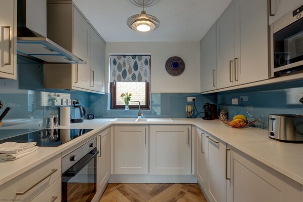 A modern kitchen with white cabinets, a built-in oven, a stainless steel toaster, and a window with a view of the outdoors.