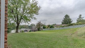 Ein gräserner Hinterhof mit einer Backsteinmauer, einem Baum und einem Haus im Hintergrund.