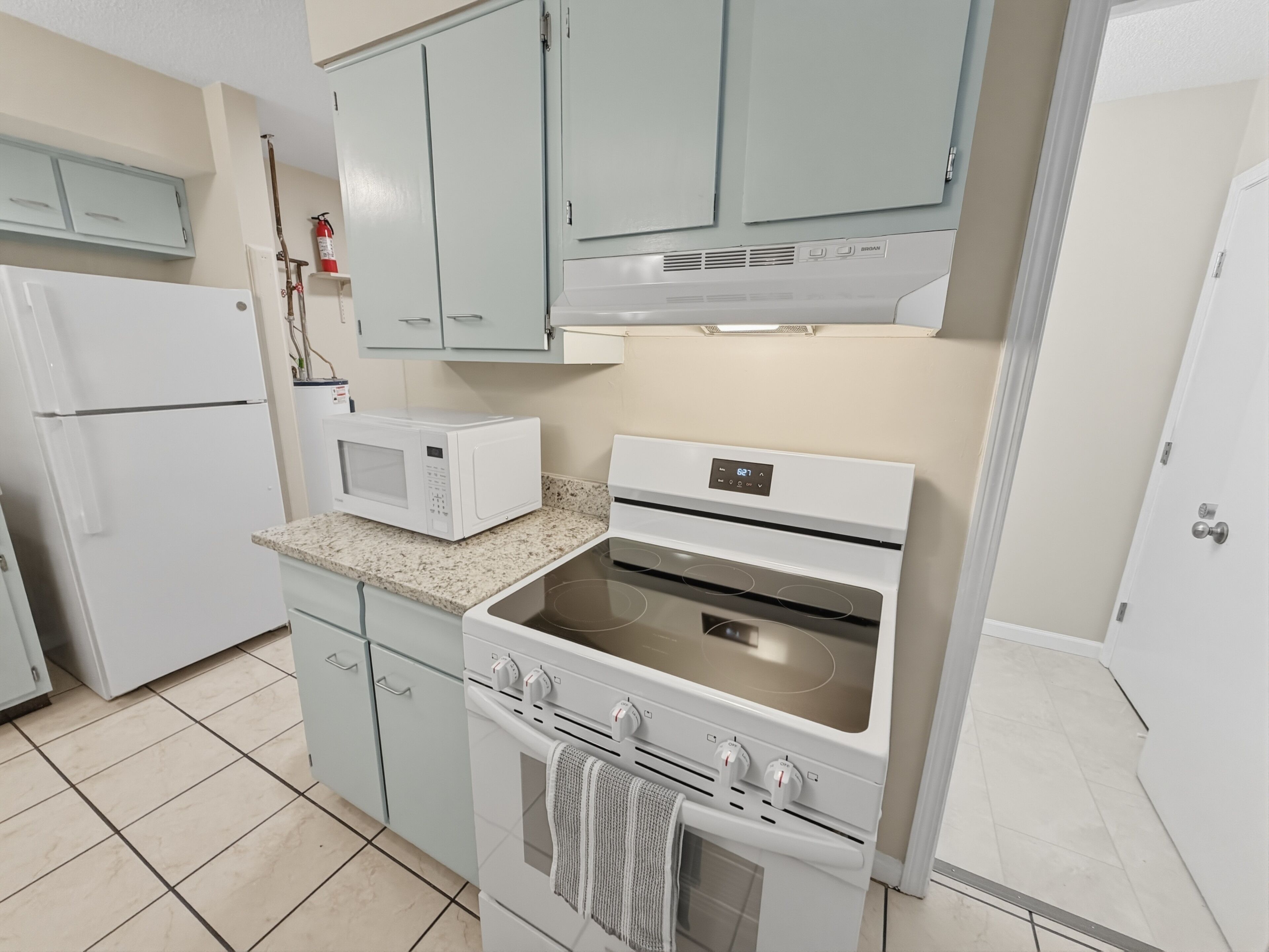 A kitchen with a microwave, oven, and refrigerator.