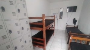 A dormitory room with bunk beds, a desk, and a wardrobe. - Hostel Canários (Palhoça)