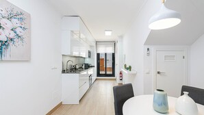 A modern kitchen with white cabinets, a black countertop, and a dining area with a white table and chairs. - Nueva I - holiday rental in Nerja (Nerja)