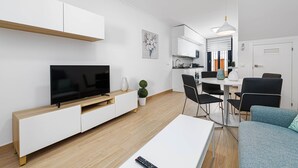 A modern living room with a flat-screen TV, a dining area with a table and chairs, and a kitchen in the background. - Nueva I - holiday rental in Nerja (Nerja)