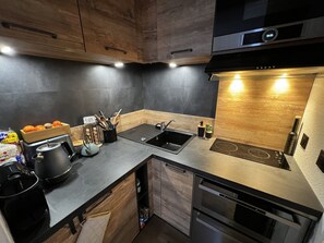 A modern kitchen with wooden cabinets, a black countertop, a built-in oven, and a sink.