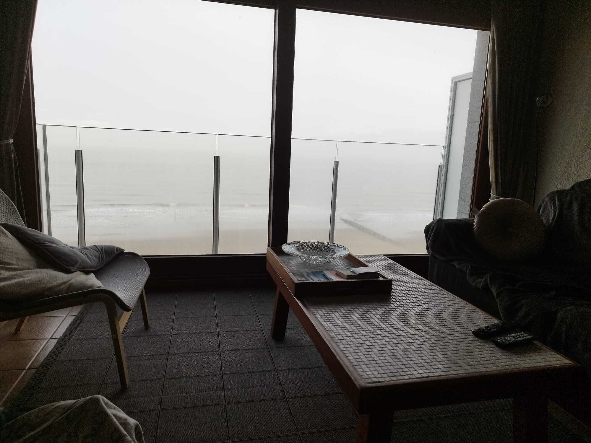 Ein Zimmer mit Meerblick, einer Couch, einem Tisch und einem fensterförmigen Vorhang.