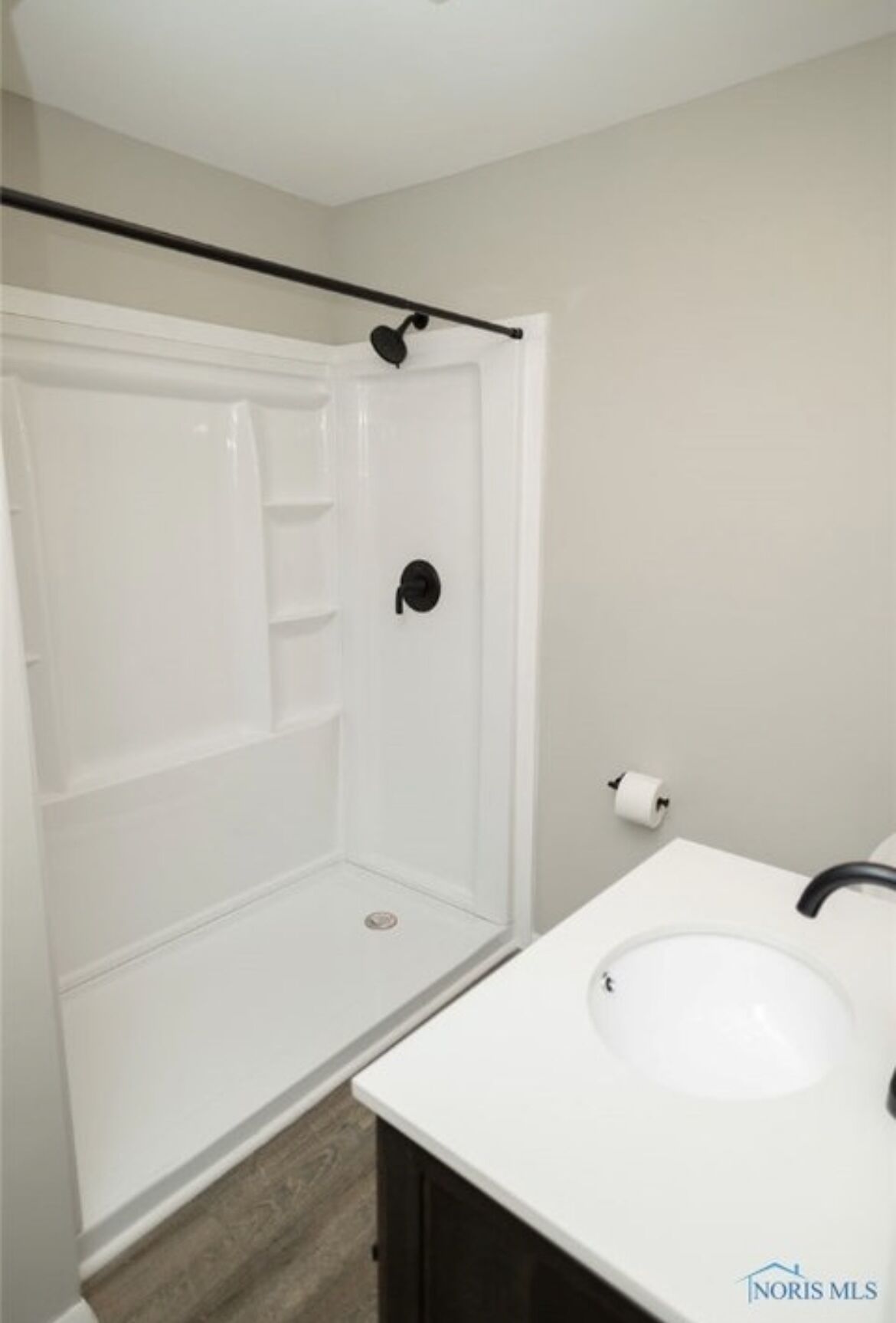 A bathroom with a white sink, a toilet, and a shower stall.