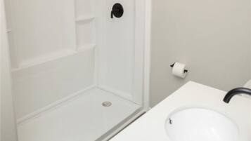A bathroom with a white sink, a toilet, and a shower stall.